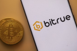 Smartphone with Bitrue logo next to a Bitcoin on an orange background