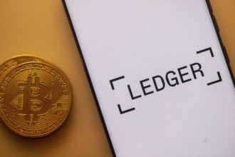 Bitcoin displayed next to a smartphone with Ledger app interface on white background
