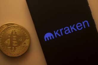 Bitcoin displayed with smartphone showing Kraken app interface on black background