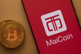 Bitcoin coin next to a smartphone featuring the MaiCoin logo on a red background