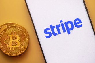 Bitcoin coin alongside a smartphone showing the Stripe logo on a light background