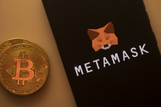 Bitcoin coin near a smartphone with the MetaMask logo on a dark background