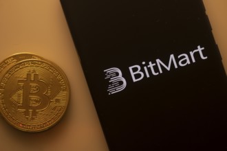 Bitcoin beside a smartphone with the BitMart logo on an orange backdrop