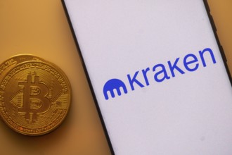 Bitcoin alongside a smartphone showing the Kraken logo on an orange backdrop