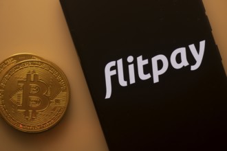 Bitcoin coin beside a black phone screen displaying the Flitpay logo