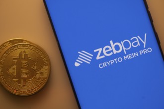 Bitcoin coin alongside a smartphone displaying the Zebpay logo on a blue screen