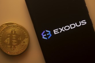 Bitcoin coin near a phone displaying the Exodus logo on a dark screen