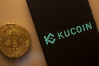 Bitcoin coin beside a smartphone screen showing the KuCoin logo against a dark background