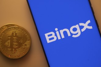 BingX app visible on a smartphone with Bitcoin coin beside it