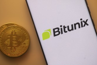 Bitunix app on phone screen next to a Bitcoin coin