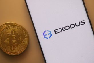 Exodus app displayed on a phone with a Bitcoin coin adjacent