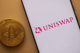Uniswap app on a phone screen with a Bitcoin coin beside it