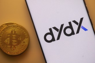 DYdX app displayed on a smartphone with Bitcoin coin on the side