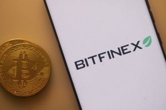 Bitfinex app visible on a phone next to a Bitcoin coin image