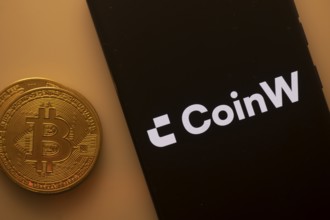 CoinW app on mobile screen alongside a Bitcoin coin
