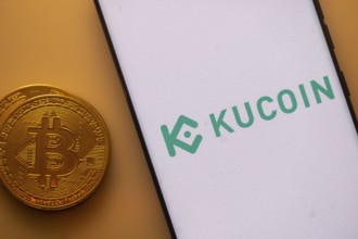 Kucoin logo displayed on a smartphone screen beside a Bitcoin coin on an orange background