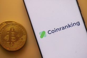Coinranking app shown on phone screen with Bitcoin coin beside it