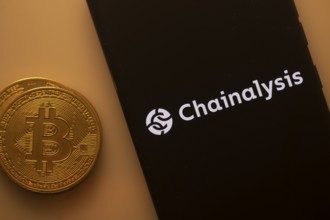 Bitcoin coin beside a black phone screen displaying the Chainalysis logo