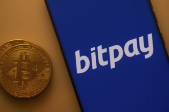 Bitcoin coin beside a blue phone screen displaying the Bitpay logo