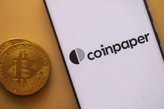 Bitcoin next to smartphone with Coinpaper app interface on white background