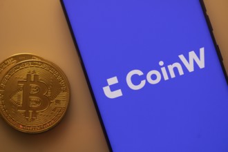 Bitcoin coin beside smartphone displaying CoinW app with purple background