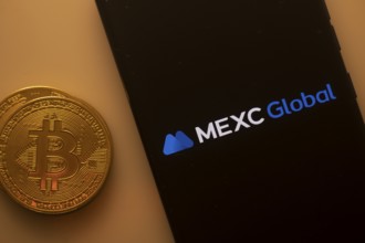 Bitcoin coin beside phone showing MEXC Global logo on a black background