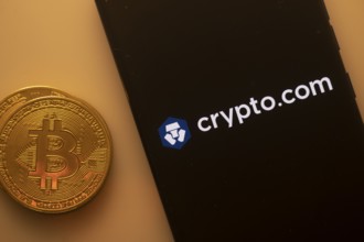 Bitcoin coin next to a phone with Crypto.com logo on black screen