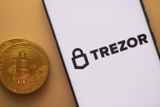 Trezor logo on phone beside Bitcoin, highlighting cryptocurrency security and storage solutions