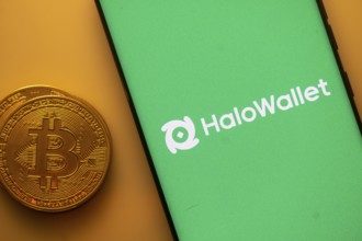 HaloWallet logo on a phone screen adjacent to a Bitcoin coin on an orange background