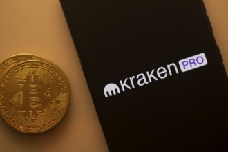 Kraken Pro logo on a smartphone screen with a Bitcoin coin on an orange background