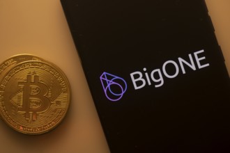 BigONE logo shown on a smartphone screen alongside a Bitcoin coin on an orange background