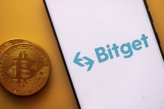 Bitget logo on a smartphone screen beside a Bitcoin coin on an orange background