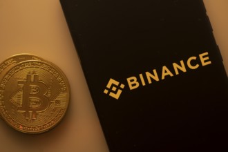 Bitcoin coin with Binance logo on a black background, linking to digital currency trading