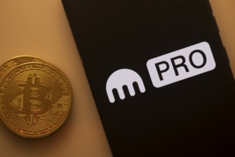 Bitcoin coin alongside phone featuring Kraken Pro logo on black background