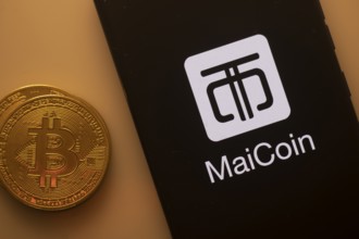 MaiCoin logo on smartphone next to Bitcoin, emphasizing cryptocurrency exchange and finance