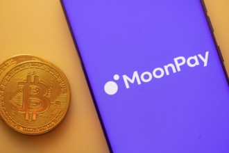 MoonPay logo on purple smartphone screen next to Bitcoin, focusing on digital payments and