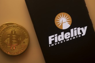 Fidelity Investments logo on phone next to Bitcoin, highlighting financial services and investments