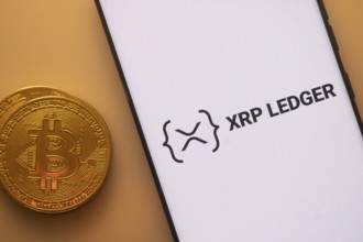 XRP Ledger logo on smartphone next to Bitcoin, emphasizing blockchain and cryptocurrency exchange