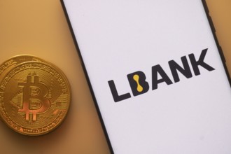 Bitcoin coin next to a phone with LBank logo on white screen