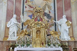 Magnificent baroque altar with golden details and statues, surrounded by ornate frescoes,