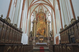 Magnificently designed church altar with rich wood carving and large painting in the background, St