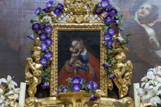Medieval religious painting in a richly decorated golden frame with flowers and angels,