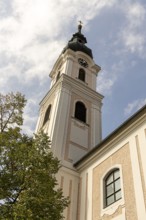 Sublime baroque tower of a church in front of a blue sky with clouds, decorated with baroque