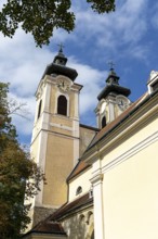 Baroque church towers with clocks rise against a clear blue sky in the afternoon light, St.Stephan