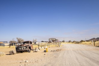 Solitaire's car graveyard in Namibia features rusted vintage cars near small desert buildings, set
