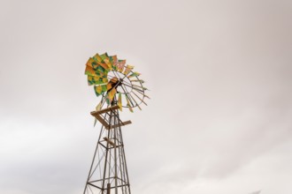 A solitary water pump stands in the arid landscape near Solitaire, Namibia, under a dramatic,