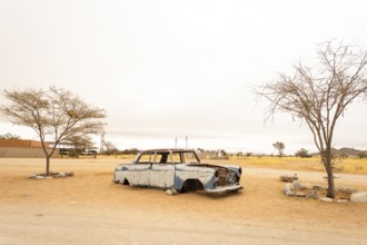 Solitaire's car graveyard in Namibia features rusted vintage cars near small desert buildings, set