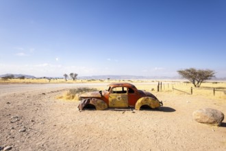 Solitaire's car graveyard in Namibia features rusted vintage cars near small desert buildings, set