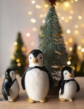 Three charming penguin figurines gather around a small christmas tree, illuminated by warm,