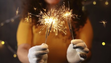 Woman wearing white gloves holding burning sparklers celebrating christmas eve, AI generated